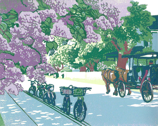 Lilac Avenue is a nine-color 10" x 8" block print with gold embellishments showcasing a dreamy street on Mackinac Island during the Lilac Festival with the wonderfully-smelling lilac bushes are in full bloom.