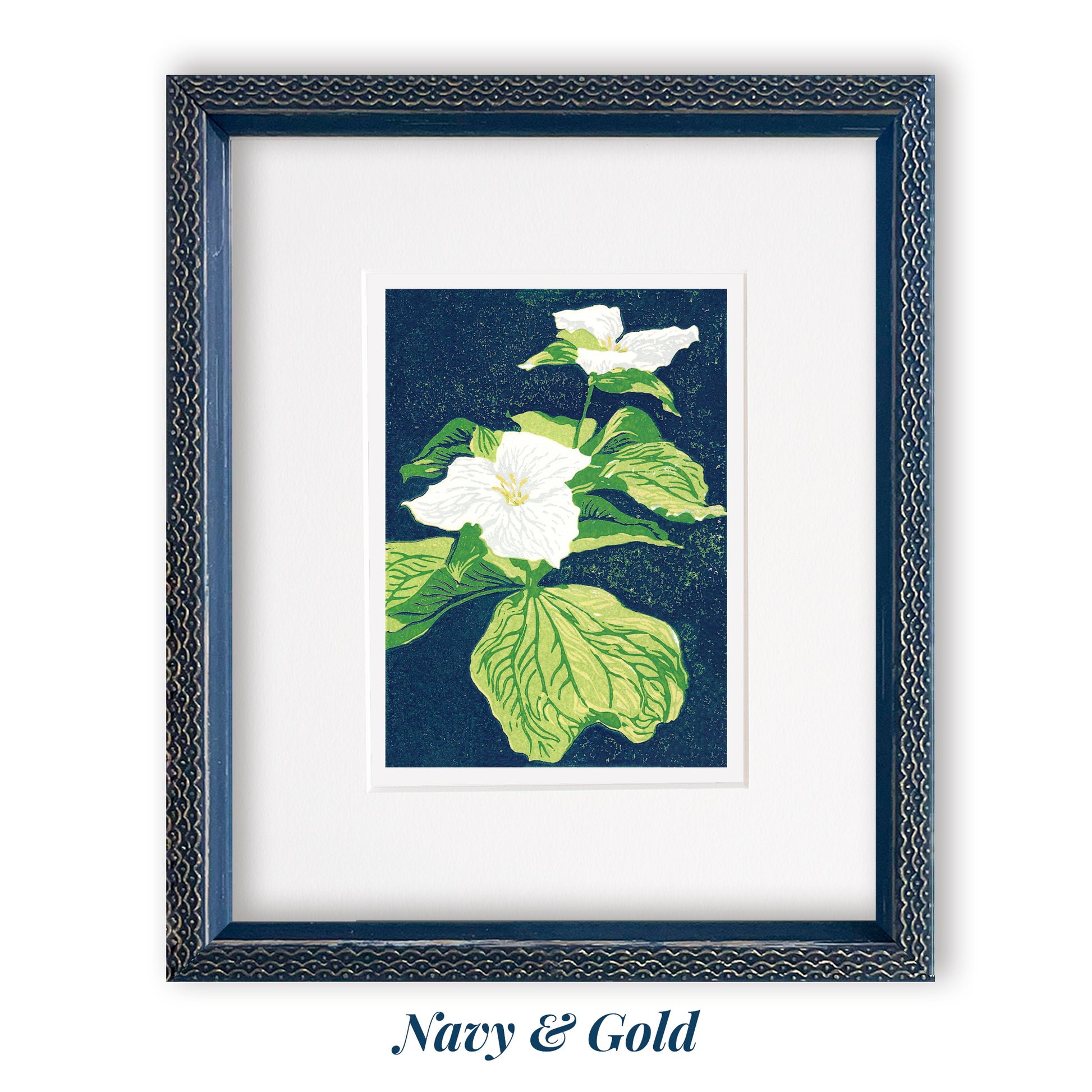A multicolor block print of two trillium wildflowers with vibrant green leaves and a navy blue background by Peninsula Prints. Framed with a white mat and a navy frame with gold embellishments.