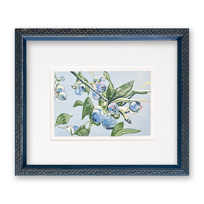 Framed artwork of blueberries and green leaves on a light blue background, with a navy blue frame.