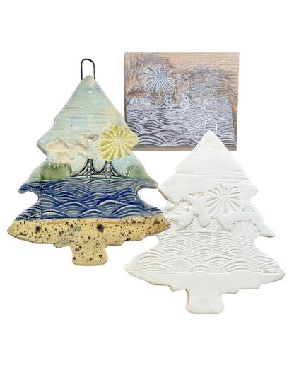 The linoleum block, and complete and in progress ceramic tree-shaped ornaments with decorative patterns on a white background.