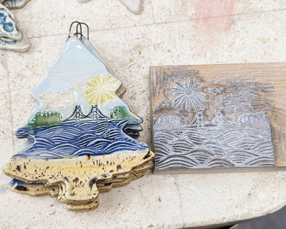 Decorative ceramic Mackinac Waves ornament next to the linoleum stamp used to create the design.