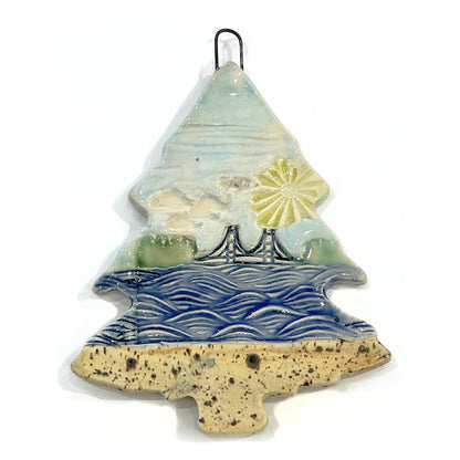 3" ceramic tree ornament featuring the Mackinac Bridge spanning the Great Lakes on a sunny day. Collaboration between Michigan artists Jeanne DeHaan and Natalia Wohletz.