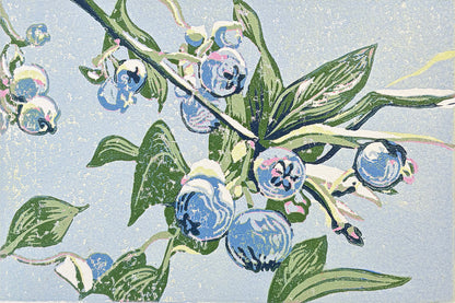 Linoleum block print of blueberries on a branch with green leaves against a light blue background.