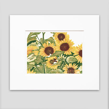 A matted multicolor block print of seven bright yellow sunflowers stand in a patch.